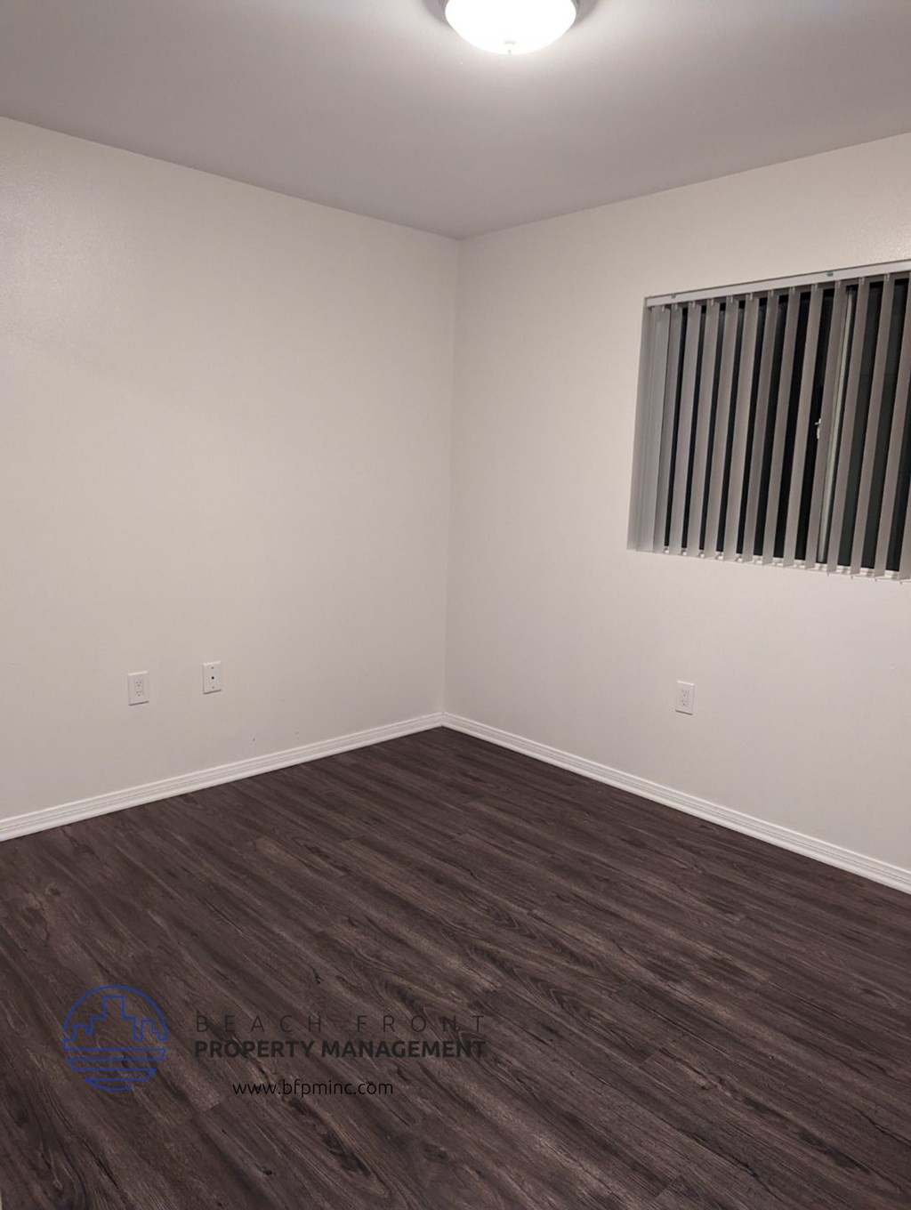 an empty room with wooden floors and a window